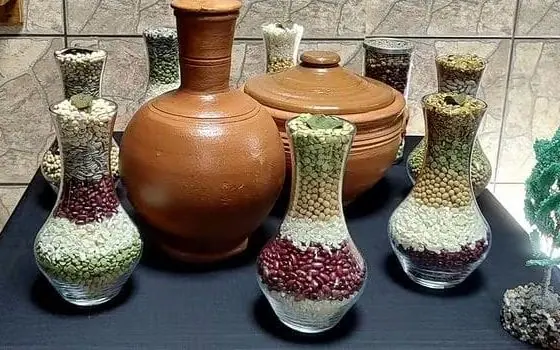 Quartinhas de barro e potes de vidro com sementes, sobre a mesa do Templo